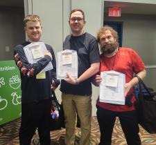 Three athletes smiling and holding up their clipboards