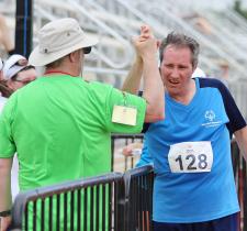 Special Olympics coach and athlete high five at a race finish line