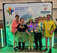 SOBC athletes smiling in neon costumes with SOBC Games banner in background