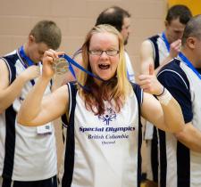 SOBC athlete Kathleen Fisher holding medal with thumbs up and smiling