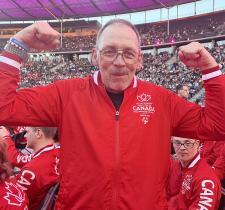 Wayne smiling and flexing both arms at the Opening Ceremony