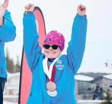 Ann smiling and holding both arms in the air on the podium