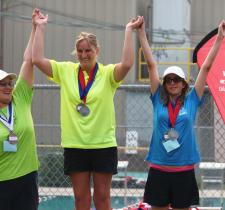 Kendall Salanski on top of podium raising hands with two other athletes
