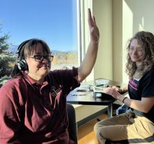 SOBC athlete with headphones on, smiling, and raising a hand up