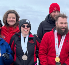 Jennifer smiling with medal around her neck with other people smiling beside her