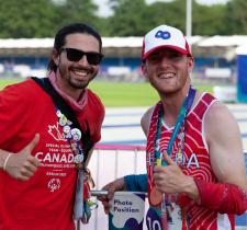 Peter holding a thumbs up with fellow athlete