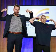 Canucks player Tucker Poolman and SOBC athlete Mike Palitti flexing their arms on stage