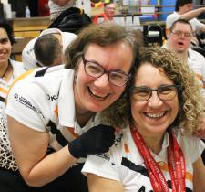 "An athlete hugs coach Susan Altomare from behind at a bowling alley."