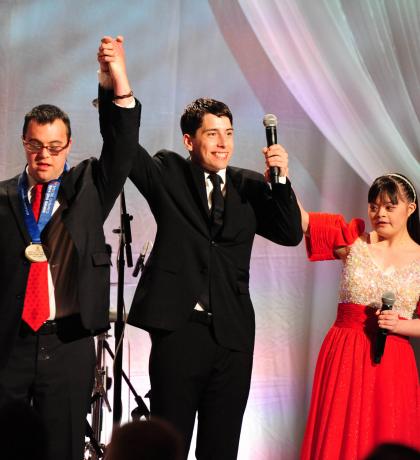 Matthew Williams on stage in formal dress with two fellow athletes