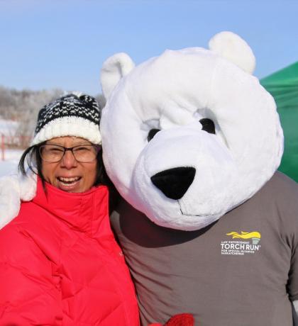 Polar Plunge Polar Bear standing next to an individual in red outside in the winter.