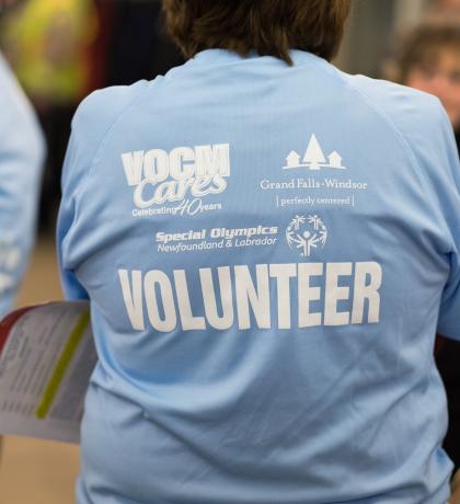 volunteer standing back on wearing a blue shirt with VOLUNTEER written in all white lettering