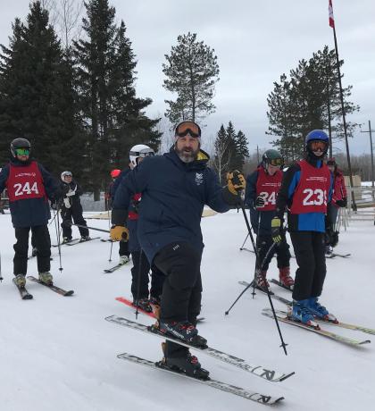 Mark Schnurr posing in his skis with four of his skiing athletes behind him