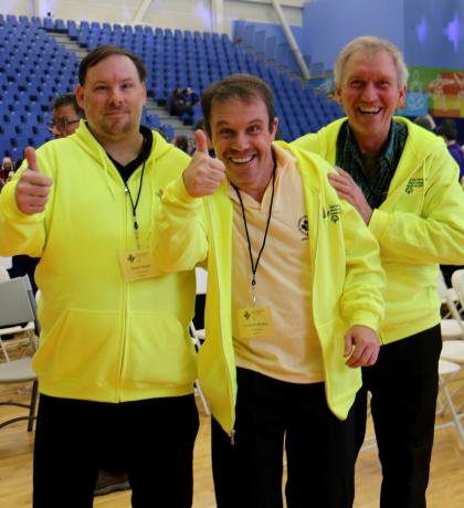 Three athletes and coaches smiling and giving a thumbs up