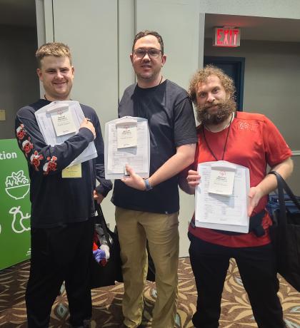 Three athletes smiling and holding up their clipboards