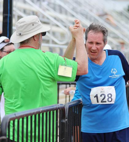 Special Olympics coach and athlete high five at a race finish line