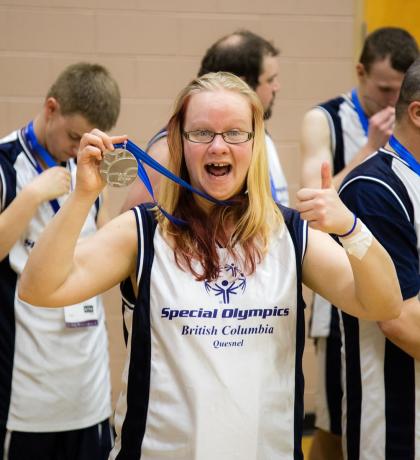 SOBC athlete Kathleen Fisher holding medal with thumbs up and smiling