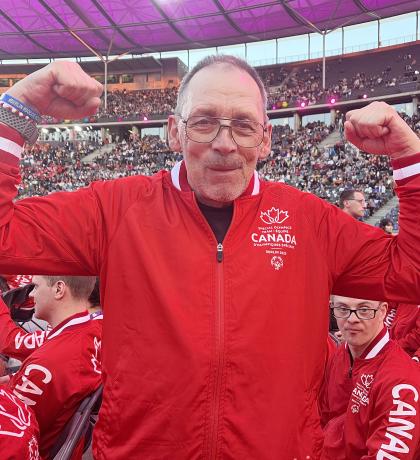 Wayne smiling and flexing both arms at the Opening Ceremony