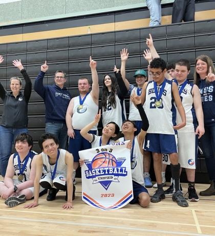 Port Moody Secondary student-athletes celebrating their first-place finish holding up their medals and banner