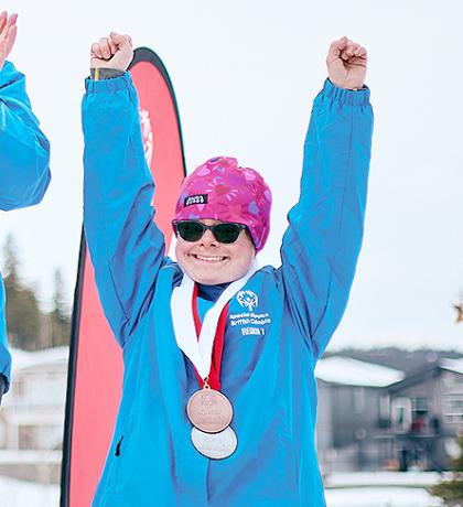 Ann smiling and holding both arms in the air on the podium