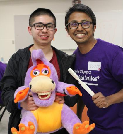 SOBC athlete Abraham Wong with dental care professional, holding a stuffed animal and tooth brush