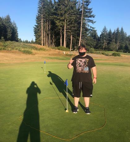 Special Olympics BC golfer standing next to a hole