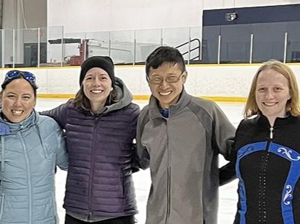 Melissa with two athletes and coach in group photo on the ice