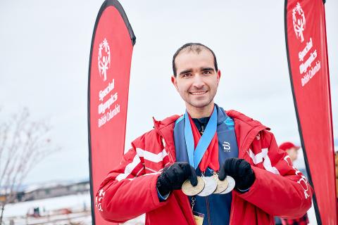Tony holding his medals and smiling