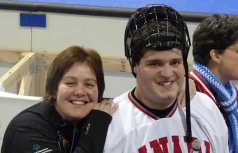 Cathy Mason rests her head on the shoulder of a Special Olympics athlete in hockey gear.