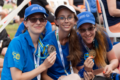 Kayley sitting with two other athletes holding medals