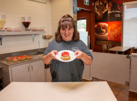 Special Olympics athlete Tori Ranson holds up a donut on a plate at TIm Hortons