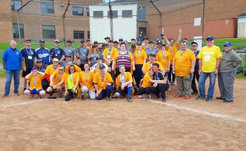 Donna Hoar poses for a team photo with Nova Scotia softball teams on a baseball diamon