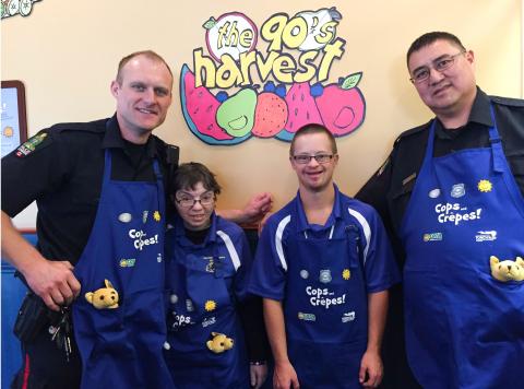 Braylon poses for a photo at Cora's restaurant for a Cops and Crepes event with another officer and two Special Olympics athletes