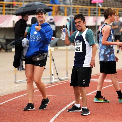 Kyle smiling on the track with a Special Olympics athlete