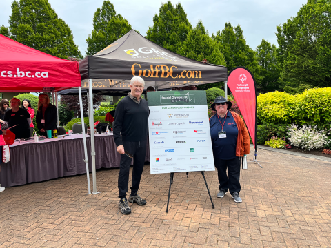 Michael Campbell and SOBC athlete standing on either side of a board with sponsor logos at SOBC Classic event