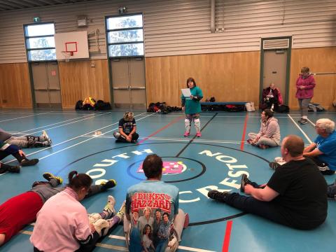 Claire holding her health poster presenting to athletes at a program with them sitting in a circle