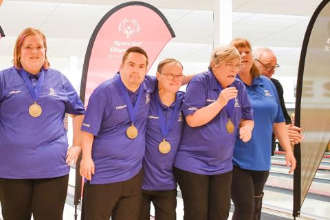 Corey and fellow bowling athletes hugging and celebrating their medals