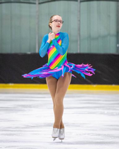 Jordyn Flamma spins on the ice on her rainbow dress.