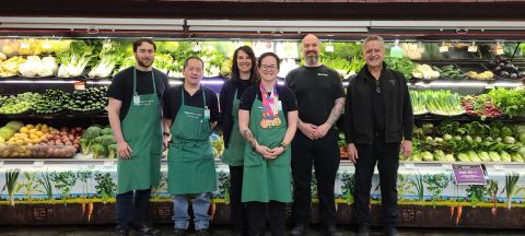 Group photo of Ashley and Thrifty Foods employees with Ashley holding her medals