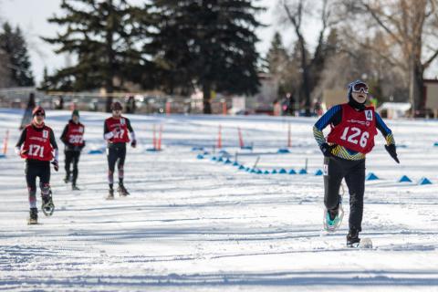 Hazen Meade racing across the snowshoe track with three snowshoers behind him