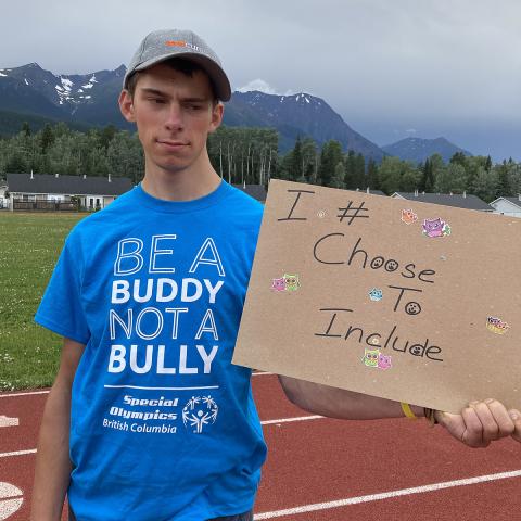 Torben Schuffert holding a handwritten sign saying "I Choose to Include"
