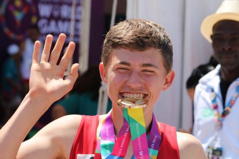 SOY athlete Darby McIntyer with medal in his mouth at the 2015 SO World Summer Games