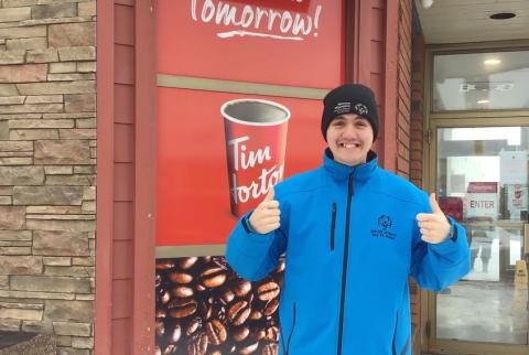 Athlete Jesse Renouf standing in front of a Tim Hortons, smiling