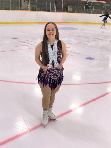 Julia Romualdi stands on the ice with her Special Olympics medals