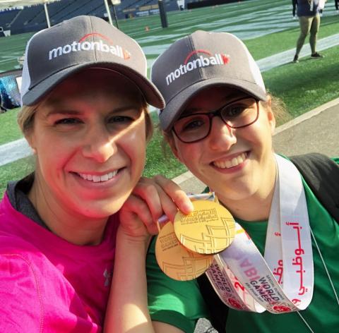 Kyla holds up a medal with a Special Olympics athlete