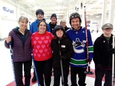 Claire smiling in group photo with other curling athletes