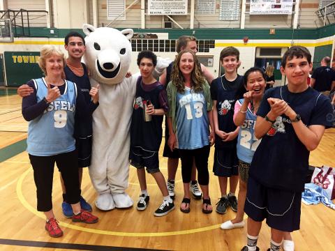 Basketball players smiling in group photo with bear mascot