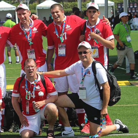 Vince Astoria kneeling next to athletes