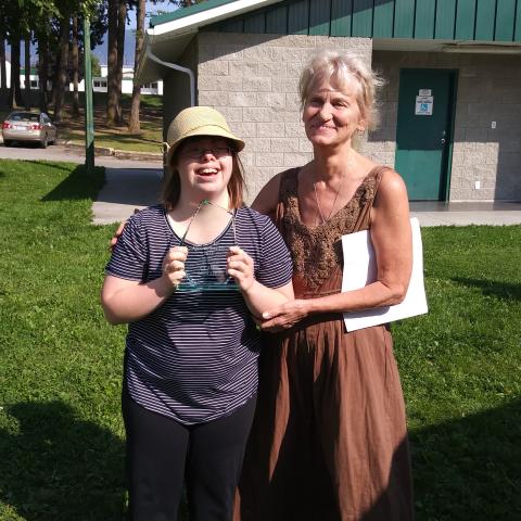 Claire holding his award and smiling