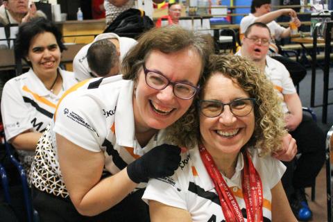 An athlete hugs coach Susan Altomare from behind at a bowling alley.