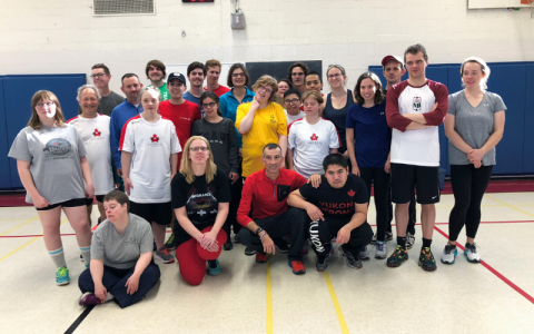 ""A group photo of Steve with a Special Olympics team in a gym""